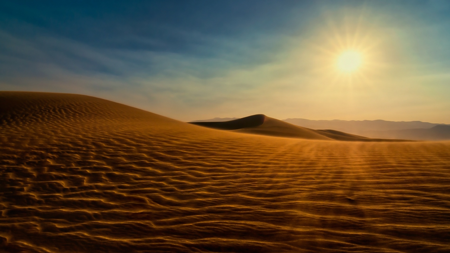 an empty desert with wavy sand hills and a glare of the bright sun